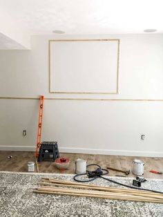 an empty room with paint and tools on the floor next to a ladder that is being used for painting