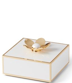 a white box with a gold ring on it's lid and an egg in the middle