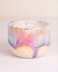 a white and pink bowl with gold speckles on it's rim, sitting on a table