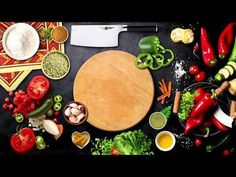 a cutting board surrounded by vegetables and spices