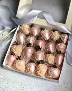 a box filled with chocolate covered strawberries on top of a table next to a ribbon