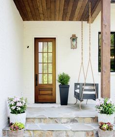 a porch with potted plants and a swing