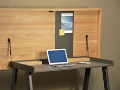 an open laptop computer sitting on top of a wooden desk next to a headboard