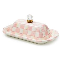 a pink and white checkered dish with a glass knob on the top, sitting on a white surface