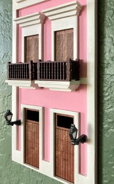 a pink and white house with two windows on the outside, and shutters on the inside