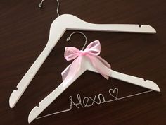 a wooden hanger with a pink bow on it