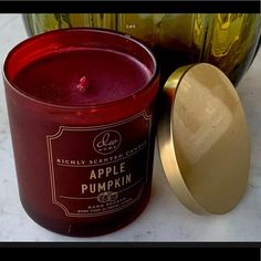 an apple pumpkin candle next to a green glass jar