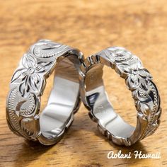 two silver wedding rings sitting on top of a wooden table