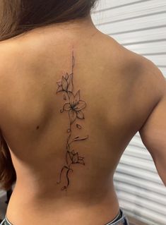 the back of a woman's lower back tattoo with flowers on her left side