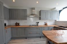 a kitchen with grey cabinets and wooden counter tops