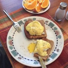 two pieces of toast on a plate with eggs and oranges