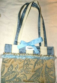 This bag is super unique, soft, and pretty.  I am not finding this brand listed.  There are no tags inside to give fabric content.  It has the ribbons inside to keep it closed (I have it tied in a bow protruding for the picture - the strips are inside), also the 2 outside straps.  The blue is the prettiest baby blue.  The stripes are sateen and something similar to a thin corduroy material.  Blue feathery trim and sequins go all the way around it.  There are 2 inner pockets.  14" x 9-1/2" with s Fabric Tapestry, Corduroy Material, Hand Bag, Baby Blue, Ted Baker Icon Bag, Feathers, Tapestry, Stripes, Purse