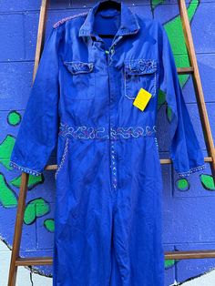 Bespoke one of a kind bright blue onesy/boiler suit; size large; hand stitched embroidery; elastic waist; cotton; 32 inch waist, 27 inch inseam; Rock and roll out to the bar, show out at the art museum - be the art that you are!   NO RETURNS.   Thank you for shopping at Tripp's Store, where fun and folks meet! Oh happy day! Blue Long Sleeve Overalls For Spring, Blue Cotton Denim Jumpsuit With Long Sleeves, Blue Cotton Long Sleeve Denim Jumpsuit, Blue Long Sleeve Cotton Denim Jumpsuit, Vintage Blue Long Sleeve Overalls, Long Sleeve Blue Cotton Overalls, Fitted Blue Long Sleeve Overalls, Hand Stitched Embroidery, Chapel Hill Nc