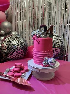 a table topped with a pink cake covered in lots of silver confetti and balloons