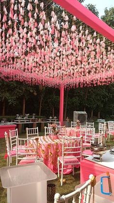 pink and white tables are set up for an outdoor wedding reception with hanging decorations on the ceiling