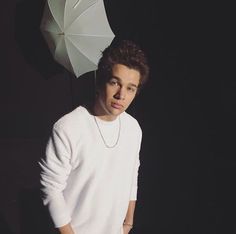 a young man standing in front of an umbrella