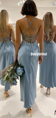 three women in blue dresses are looking at each other and one is holding a bouquet