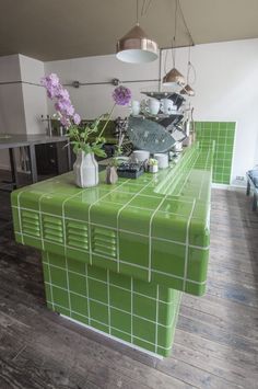 a kitchen with green tiled counter tops and wooden floors