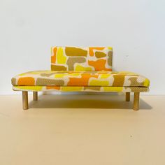 an orange and yellow couch sitting on top of a wooden table