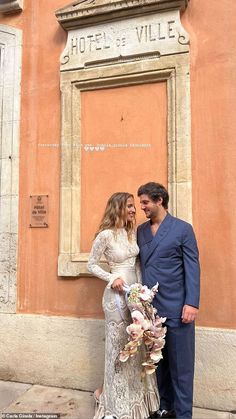 a man and woman standing next to each other in front of a building