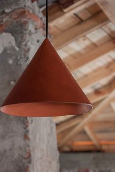 a light hanging from the ceiling in a room with exposed concrete walls and wooden beams