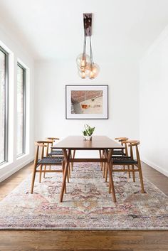 a dining room table with chairs and a rug on the floor