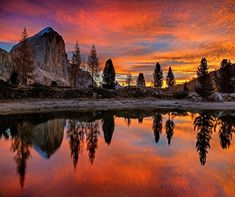 an image of a beautiful sunset with mountains in the background and trees reflected in the water