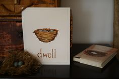 a card with a bird's nest on it next to a book that reads dwelll