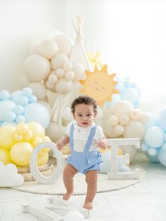 a baby is standing on the floor in front of balloons and letters that spell out o