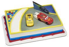 a birthday cake with cars on it and a book in the shape of a race track