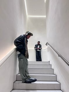 two men are standing on some stairs and one is looking at something in the distance