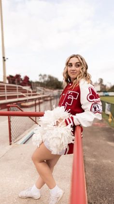 a woman in a cheerleader outfit posing on the sidelines at a football game