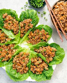 lettuce wraps with meat and vegetables on a plate next to chopsticks