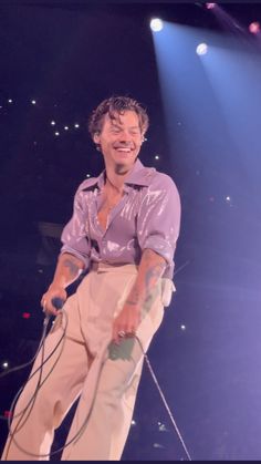 a man standing on top of a stage with a microphone in his hand and smiling at the camera