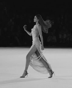 a woman is walking down the runway in a white dress