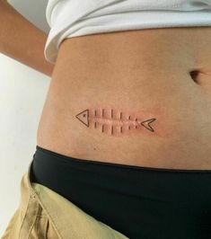 a woman's stomach with an arrow tattoo on the lower part of her belly