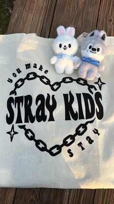 two stuffed animals sitting on top of a white tote bag that says stray kids