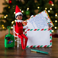 an elf sitting in a chair next to a christmas letter