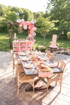 a table set up for a party with pink balloons