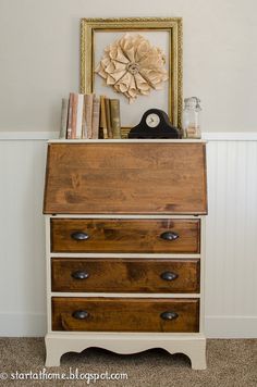 an old dresser is painted white and has some books on top of it, along with a clock