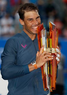 a male tennis player is holding his trophy