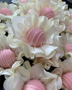 pink and white flowers are arranged on a black table top with chocolates in the middle