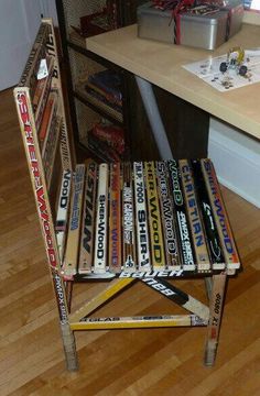 a stack of baseball bats sitting on top of a wooden chair next to a desk