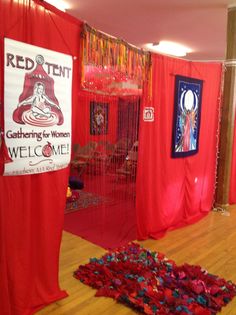 a room with red curtains and a welcome sign on the wall next to an area rug