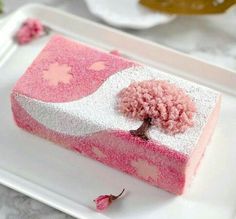 a piece of cake with pink frosting and a small tree on top is sitting on a white plate