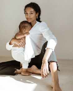 a woman sitting on the floor holding a baby