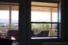 an open window with the view of mountains out into the distance and furniture on the porch