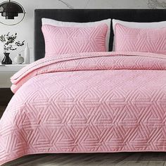 a bed with pink bedspread and pillows in a room