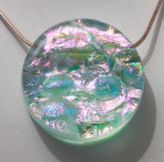 "Large Dichroic Moon Pendant in my Space Opal 7 color style.  Two layers of dichroic glass, multiple firings and cold working to shape and smooth each piece comes together to create these pendants.  Fire polished to give a very subtle texture on top.   Comes with an 18\" silver filled snake chain. The Space Opal color line came from extensive testing of color pairs of dichroic glass and frit.  Only the most intriguing color combinations were selected to be part of my color line.   The channel is fired into the glass and will accommodate up to a 2mm chain or cord.  Pendant size is approximately 1.25\" dia." Iridescent Round Glass Jewelry, Iridescent Glass Round Jewelry, Celestial Pendant, Dichroic Pendant, Pink Pendant, Color Pairs, My Space, Opal Color, Valentines Gifts For Her