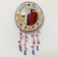 a mirror hanging from the side of a wall with beads and chains attached to it